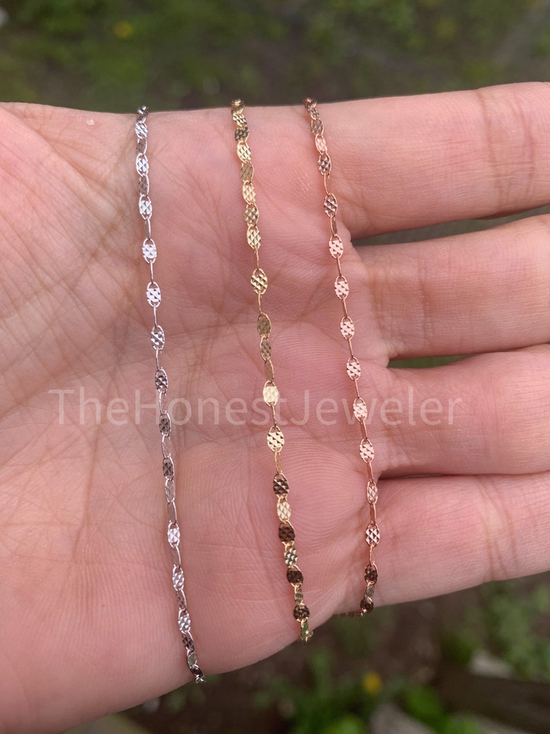 May include: Three delicate gold chains with a textured oval link design. The chains are silver, gold, and rose gold.