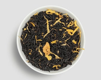 May include: A white bowl filled with black tea leaves and dried orange peel.