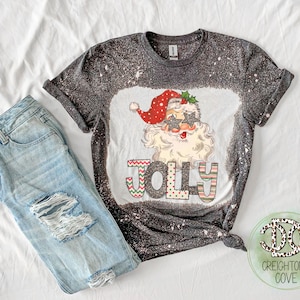 May include: A black t-shirt with a white bleach design featuring a cartoon Santa Claus wearing sunglasses and the word "Jolly" in colorful letters.