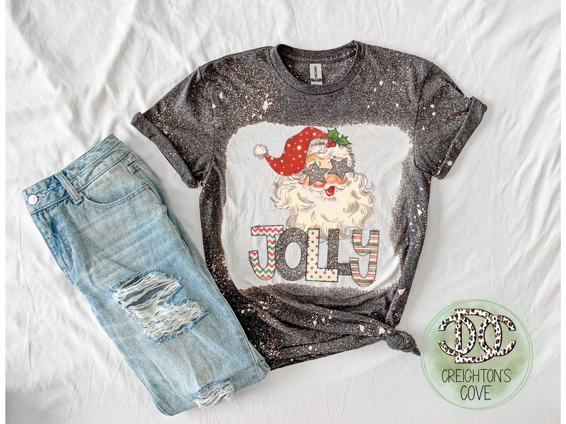 May include: A black t-shirt with a white bleach design featuring a cartoon Santa Claus wearing sunglasses and the word "Jolly" in colorful letters.