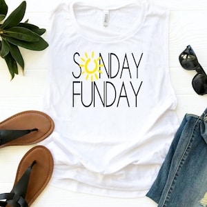 Peut inclure: D&eacute;bardeur blanc avec les mots "SUNDAY FUNDAY" en lettres noires et un soleil jaune. Le haut est sans manches et a une coupe d&eacute;contract&eacute;e. Des lunettes de soleil noires et un jean bleu sont &agrave; c&ocirc;t&eacute; du haut. Des sandales marron sont en bas.