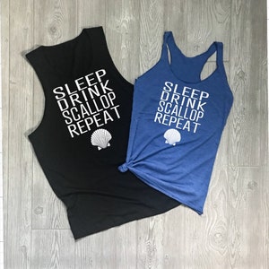 May include: Two sleeveless tank tops with the text "SLEEP DRINK SCALLOP REPEAT" and a white seashell graphic. The tank tops are black and blue.