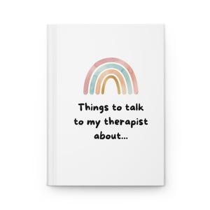 May include: White journal with a watercolor rainbow design in pastel colors. The text "Things to talk to my therapist about..." is printed in black below the rainbow.