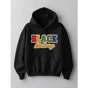May include: Black hoodie with a front pocket and a drawstring hood. The front of the hoodie features the words "BLACK history" in colorful, textured lettering. The word "BLACK" is in red, orange, green, and blue. The word "history" is in a yellow script font.