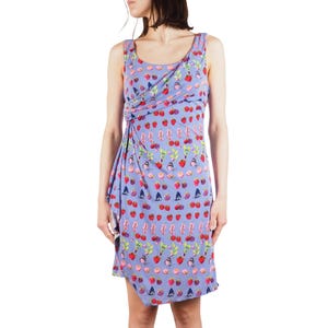 May include: A sleeveless, knee-length dress in a light purple hue, adorned with a playful pattern of strawberries, cherries, and other fruit motifs. The dress features a draped design at the neckline and waist, adding a touch of elegance to the casual style.