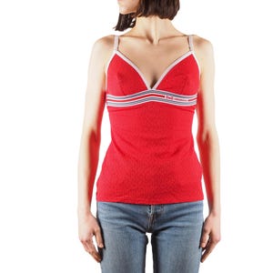 May include: A red spaghetti strap tank top with white and blue stripes and the text "D&G JUNIOR" on the front. The tank top is worn over blue jeans.
