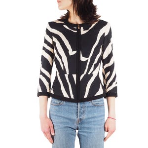 Puede incluir: Una chaqueta negra y blanca con estampado de cebra y cierre de cremallera. La chaqueta tiene una silueta ajustada y una longitud recortada.