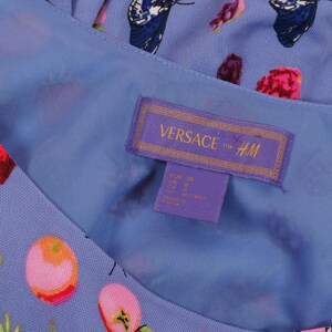 May include: A light blue dress with a floral and butterfly pattern. The dress features a tag with the text "VERSACE for H&M". The tag also includes size information.