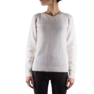 May include: A white fuzzy sweater with a round neckline and long sleeves.