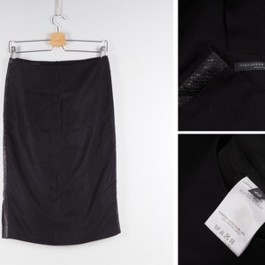 May include: Black pencil skirt with a sequined detail on the side. The skirt has a label that reads "Alexander McQueen".