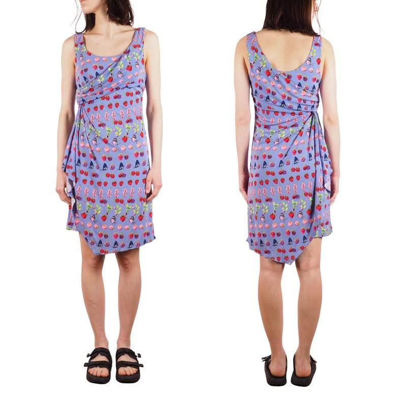 May include: A sleeveless, lavender dress with a wrap-style design. The dress features a repeating pattern of red strawberries, green leaves, and other small, colorful motifs. The hemline is asymmetrical.