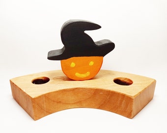 May include: Wooden Halloween candle holder with a pumpkin face wearing a black witch hat. The holder has two holes for candles.