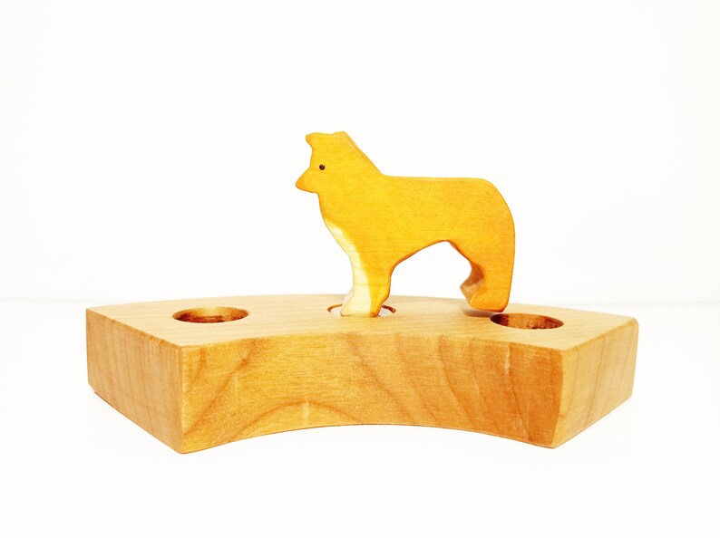 May include: A wooden toy with a yellow dog standing on a wooden base with three holes. The dog is made of wood and has a simple design.