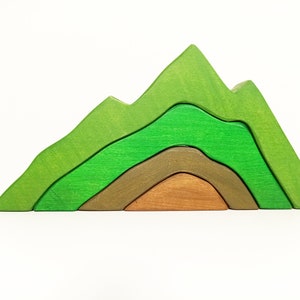 以下が含まれることがあります： 緑と茶色の木製の層でできた木製の玩具の山。山は、互いに嵌合する5つの部分で構成されています。