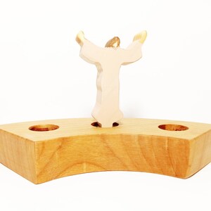 Peut inclure: Bougeoir en bois avec deux coupelles à bougies et une figurine en bois d'une personne les bras levés en l'air.