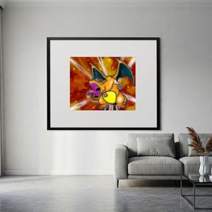May include: Framed artwork featuring a cartoon Charizard character in orange, yellow, and blue. The artwork has a fiery background with radiating light beams. The image is framed in a black border and displayed on a white wall.