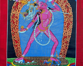 May include: A vibrant painting of a pink deity with multiple arms, adorned with gold jewelry and a white skull necklace. The figure stands against a blue and gold backdrop, holding a sword and a skull cup. The artwork is framed in red and features the text "Himalayan Healers".