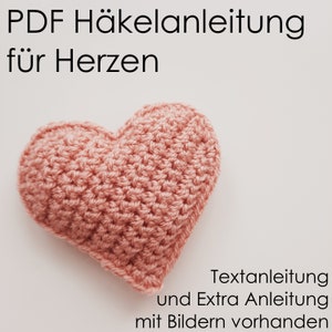 Könnte beinhalten: Ein pinkfarbenes gehäkeltes Herz mit dem Text "PDF Häkelanleitung für Herzen" und "Textanleitung und Extra Anleitung mit Bildern vorhanden" am unteren Rand des Bildes.
