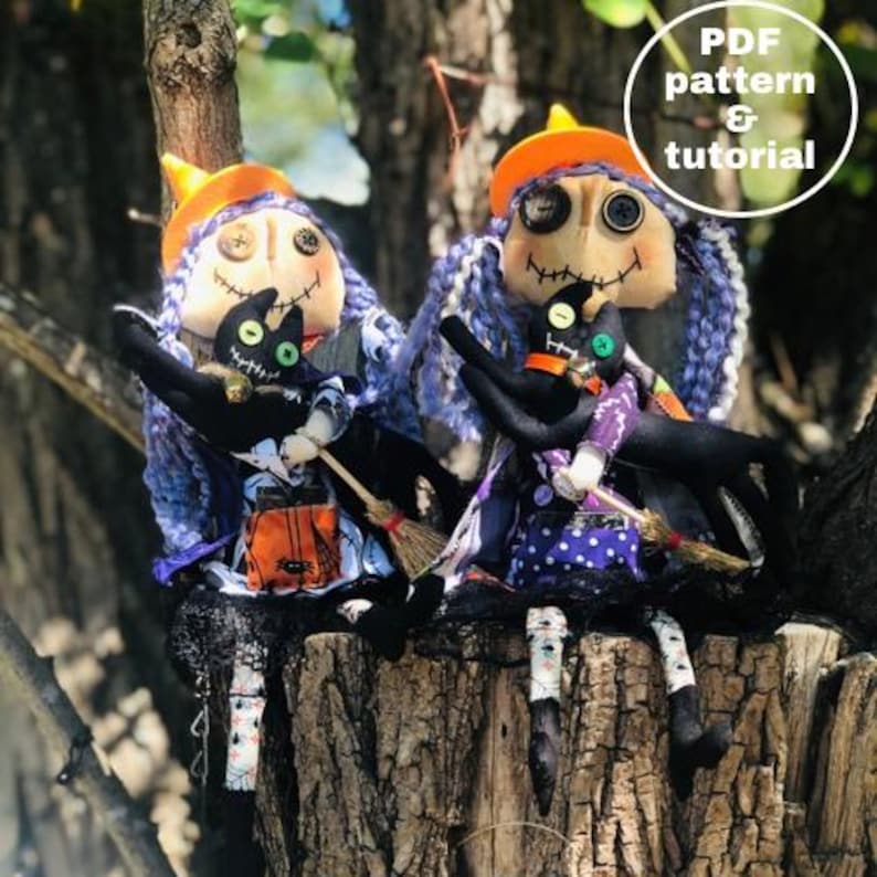 Op de afbeelding: Twee handgemaakte lappenpoppen gekleed als heksen met zwarte katten. De poppen dragen paarse en zwarte jurken met oranje hoeden en hebben zwart garenhaar. De poppen zitten op een boomstam.  PDF-patroon & tutorial.