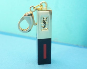 Charm/breloque "Bâton de rouge à lèvres YSL", Yves Saint Laurent, métal et plastique, coloris noir, doré et rouge.