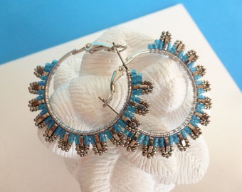 Créoles tissées à l'aiguille, perles miyuki en verre (rocailles et half Tila), coloris argenté, gunmetal (gris acier) et bleu.