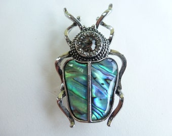 Broche rétro "Scarabée", métal, coquillage et verre, coloris argenté, vert/violet/beige et noir.