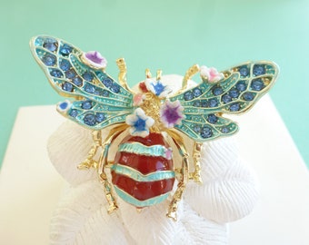 Broche émaillée "Abeille et fleurs", métal et verre, coloris bleu aigue marine, bleu asphir, rouge carmin, blanc, violet et doré.