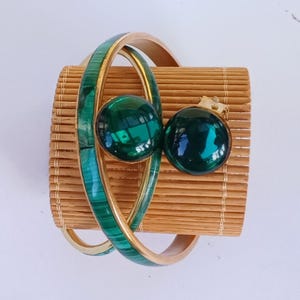 Peut inclure: Un ensemble de bijoux unique comprenant un bracelet de style bambou avec un design vert malachite et or, et deux boucles d'oreilles rondes en verre vert assorties. Le bracelet a une bande dorée et une incrustation de malachite verte.