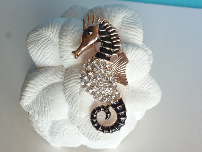 metal and glass gold colour slightly pinkish and black. Enamelled brooch Seahorse