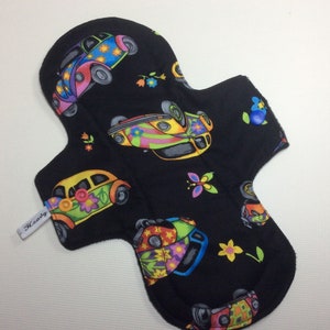 以下が含まれることがあります： カラフルなヴィンテージフォルクスワーゲン、花、蝶のプリントが施された黒い布製のリサイクル可能なパッド。パッドには「Heavy」と書かれたラベルが付いています。