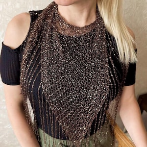 May include: A brown sequined scarf with a triangular shape. The scarf is made of a delicate, net-like material and is adorned with small, shimmering sequins. The scarf is draped over a black top.