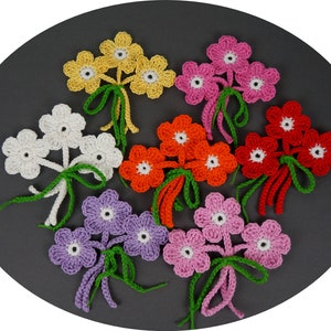 May include: A set of seven crocheted flower bouquets in various colors, including yellow, white, orange, red, pink, and purple. Each bouquet features three flowers with green stems.