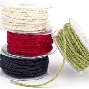May include: Four spools of twine in different colours: natural, red, black, and green. The twine is wound around clear plastic spools.