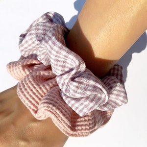 May include: Two pink and white patterned scrunchies, one with a striped pattern and the other with a textured pattern.