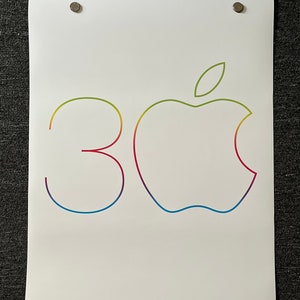 May include: White poster with the Apple logo and the number "30" in a rainbow gradient. The text "Happy Birthday, Mac." is printed at the bottom. The poster is held in place by four magnets.