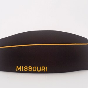 May include: A black fabric hat with a gold trim and the word "MISSOURI" embroidered in gold.