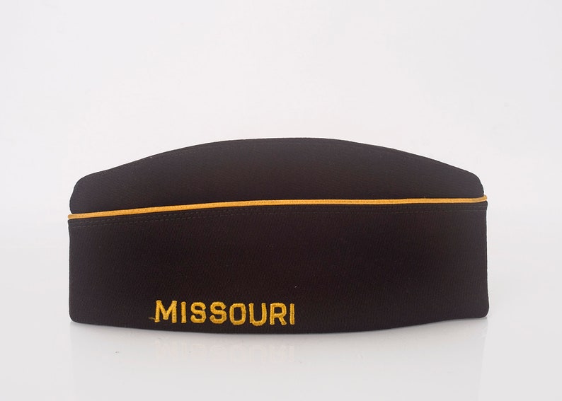 May include: A black fabric hat with a gold trim and the word "MISSOURI" embroidered in gold.
