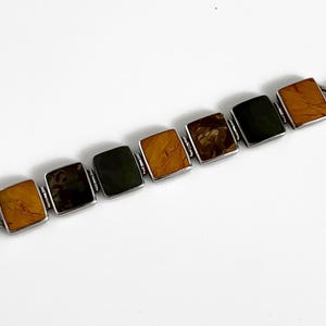May include: A silver bracelet with alternating brown and green square stones. The bracelet has a t-bar clasp.