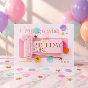 Peut inclure: Une carte d'anniversaire avec l'inscription "Birthday Girl" sur un ruban rose, entourée de confettis colorés et de ballons. La carte présente un chiffre "1" duveteux et les mots "Make a wish".