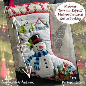 May include: A medium Christmas quilted stocking with a snowman design. The stocking is approximately 46 cm high and has a red trim. The design includes a snowman with a black top hat and blue scarf, a house, and Christmas presents. The text "Makower Snowman Express" is visible.