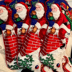 May include: Set of three red and white Christmas stockings with a blue background featuring Santa Claus climbing down a brick chimney. Each stocking has a green holly sprig and a white trim.
