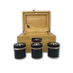 May include: A bamboo stash box with a combination lock and three black jars with silver lids. The box is open, revealing a compartment. The jars have a white leaf design on the lids.