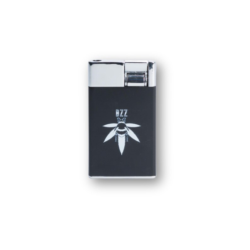 May include: A black and silver lighter with a white graphic of a bee and cannabis leaf. The word "BZZ" is above the graphic. The lighter has a rectangular shape with a silver top.