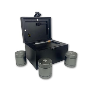 May include: A black box with an open lid, containing a glass tube with a cork. Three grey cylindrical containers with a leaf logo are arranged around the box. The text "THE BIZ" is on the containers.