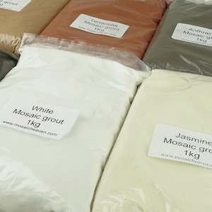 May include: Six bags of 1 kg mosaic grout in various colours: beige, terracotta, grey, white, and cream. The bags are labelled with the colour and weight. The bags are all on a white surface.