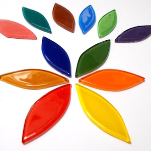May include: A selection of leaf-shaped glass tiles in a variety of colours, arranged in a circular design. The tiles include shades of red, orange, yellow, green, blue, and purple. These decorative tiles are suitable for mosaic art projects.