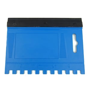 May include: A blue plastic tool with a black rubber handle. The tool has a ruler marked in inches and a series of evenly spaced teeth along the bottom edge.