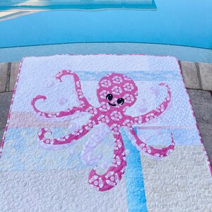 Pink baby octopus applique quilt made with both sides of pink fishbone and sand dollar fabric.