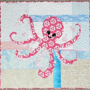 Octopus applique quilt pattern made with both sides of pink fishbone and sand dollar fabric.