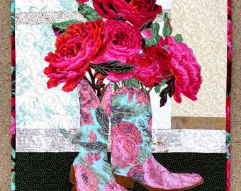 May include: A rectangular fabric wall hanging featuring a quilted design of two light blue cowboy boots adorned with pink floral patterns, overflowing with a vibrant bouquet of deep red and magenta peonies against a patchwork background.